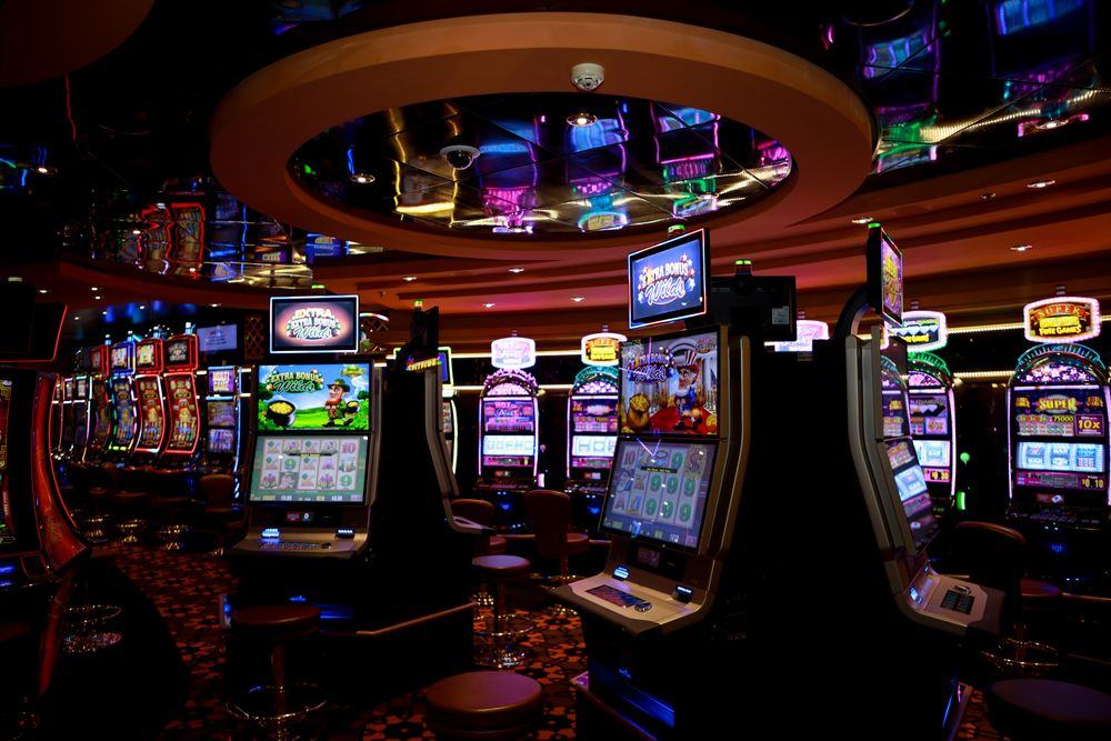 Deretan mesin slot berwarna-warni di lantai kasino
